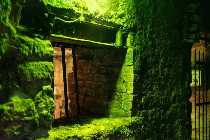 A view through a barred window in a stone wall, green lighting.